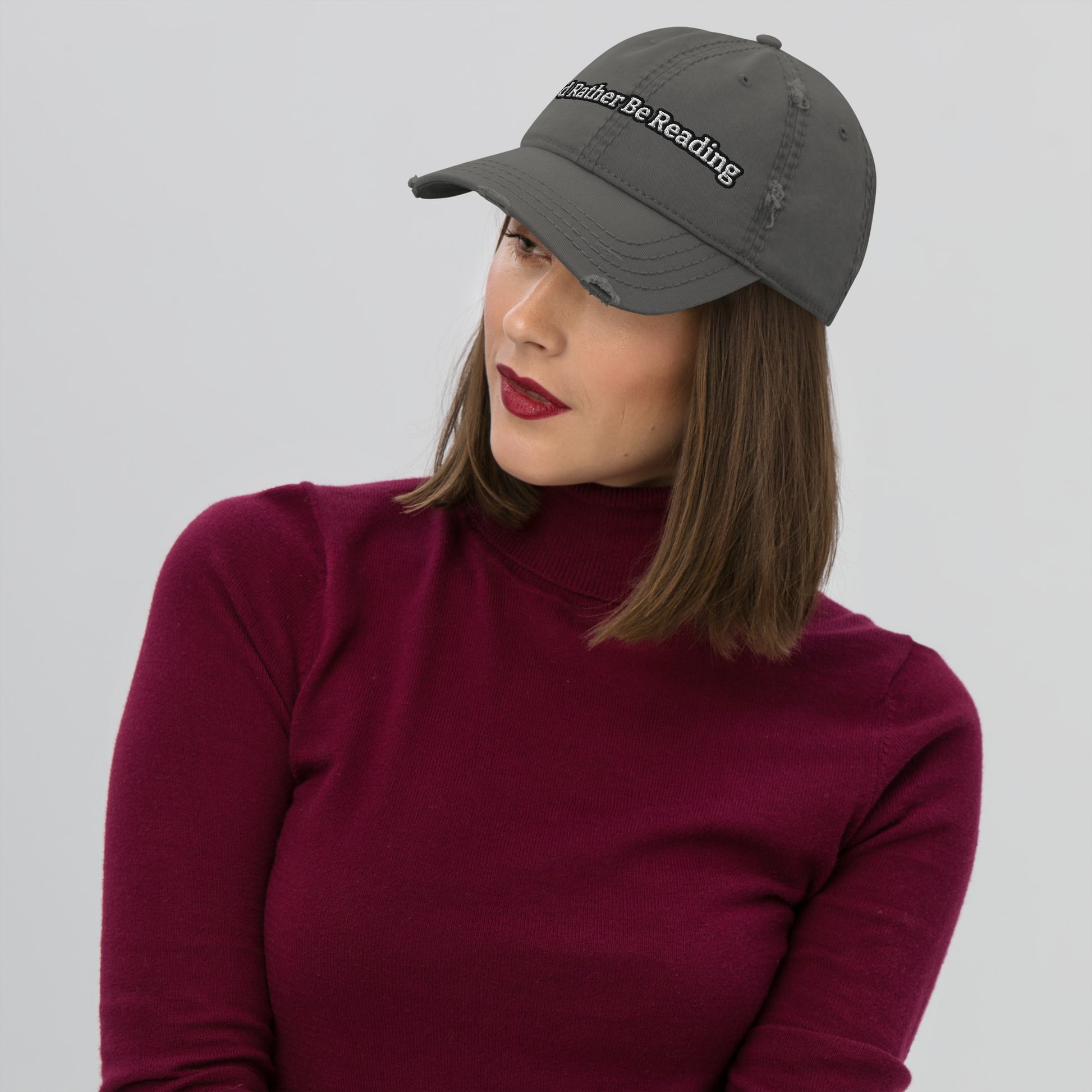 A grey distressed hat with a faded, worn appearance, featuring the text 'I'd rather be reading' in a casual, playful font."