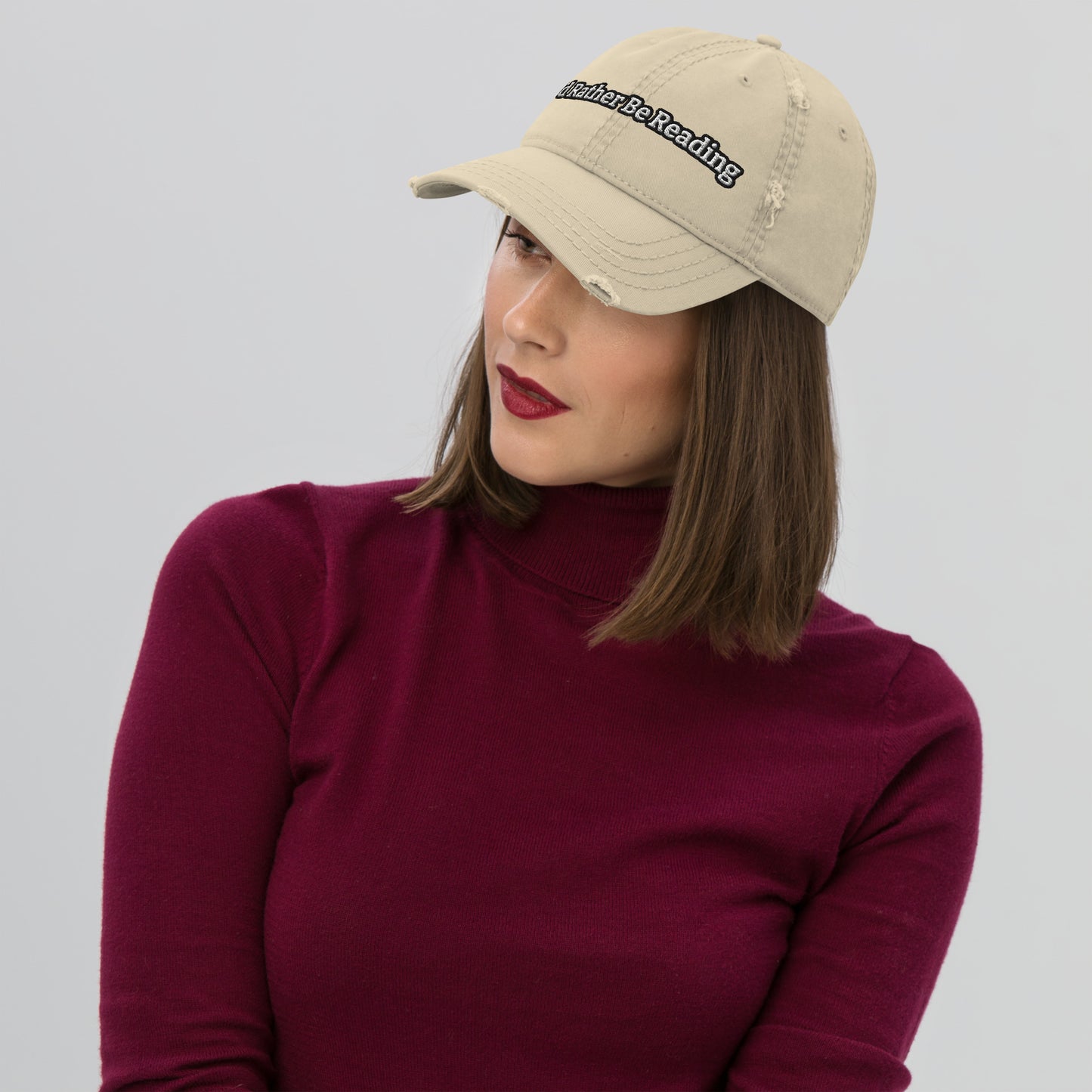 A khaki distressed hat with a faded, worn appearance, featuring the text 'I'd rather be reading' in a casual, playful font."